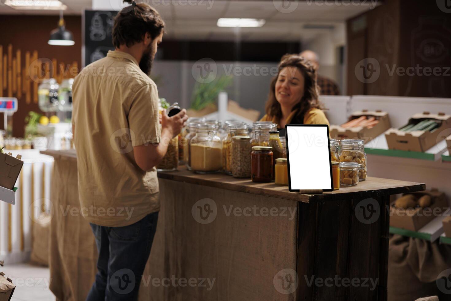 Mockup tablet with empty copy space used as advertising sign in zero waste supermarket full with customers shopping for healthy food. Isolated screen device in local neighborhood store photo
