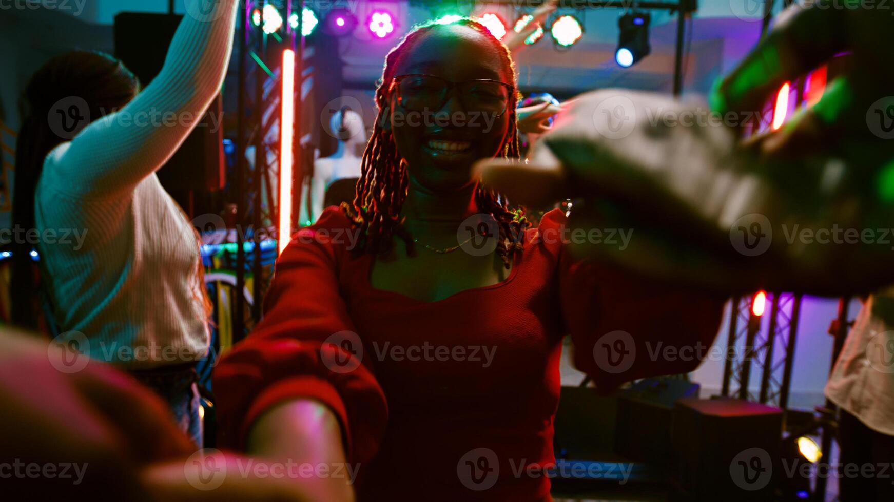 POV of girl dancing with someone at club, enjoying disco party on discotheque dance floor. Group of friends having fun at nightclub listening to electronic music, entertainment. Handheld shot. photo