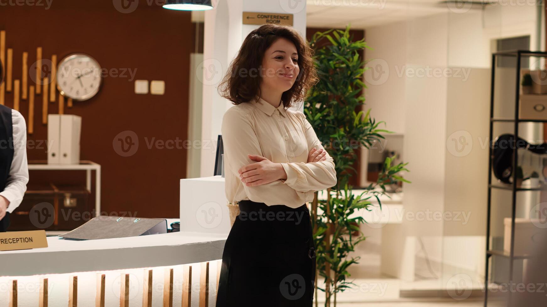 Smiling hotel manager handing folders of tourist accommodation travel booking paperwork to happy receptionist. Cheerful professional staff working in modern resort lobby. photo