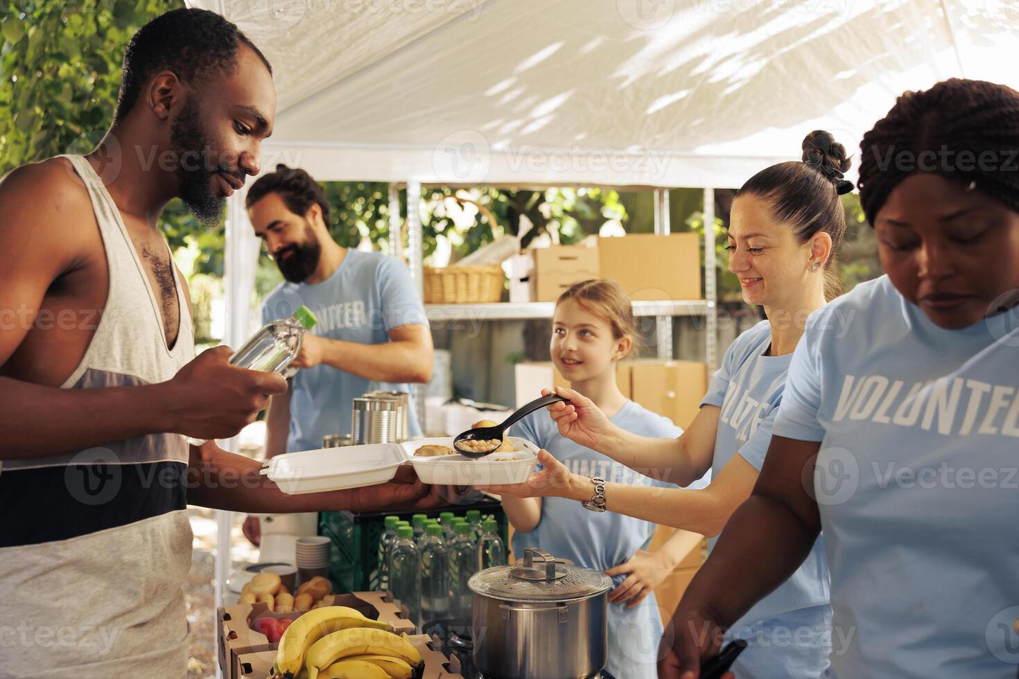 Young african american and caucasian volunteers donate free food and essential items to the less fortunate. Friendly voluntary people provide hunger relief and humanitarian aid at homeless shelter. photo