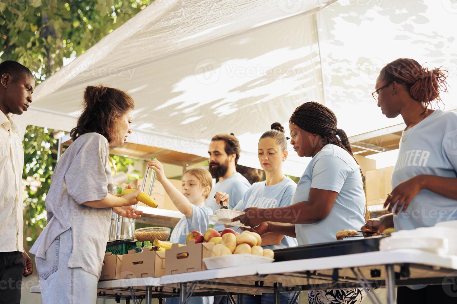 Multicultural hunger relief team distribute free food to the needy providing assistance and support to homeless people. Volunteers serving warm meals, aiming to alleviate hunger and poverty. photo