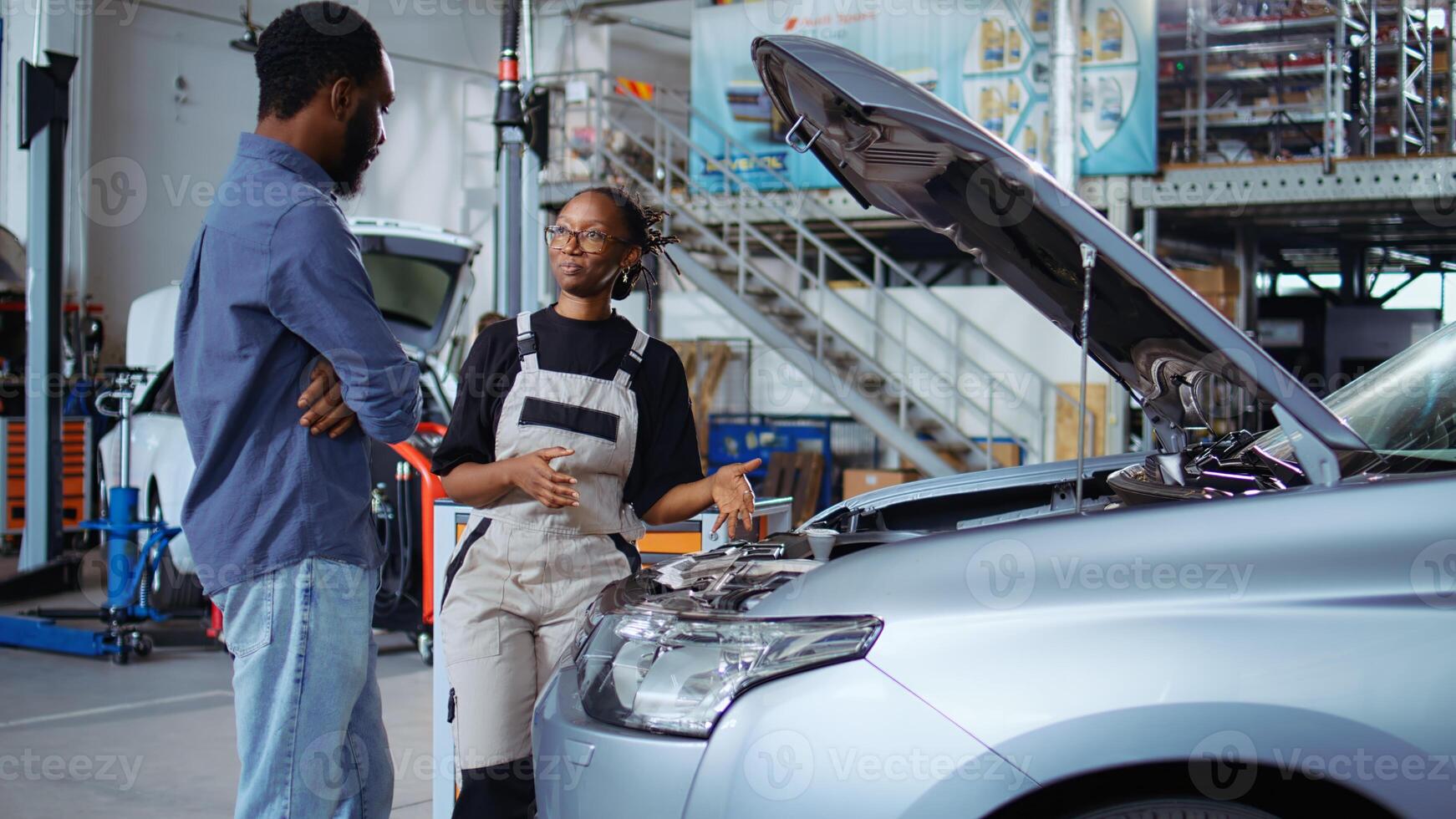 calificado ingeniero escucha a cliente en reparar comercio, utilizando ordenador portátil a escribir abajo coche modificaciones necesario. profesional en garaje lugar de trabajo con cliente, escuchando a su peticiones para vehículo Afinación foto