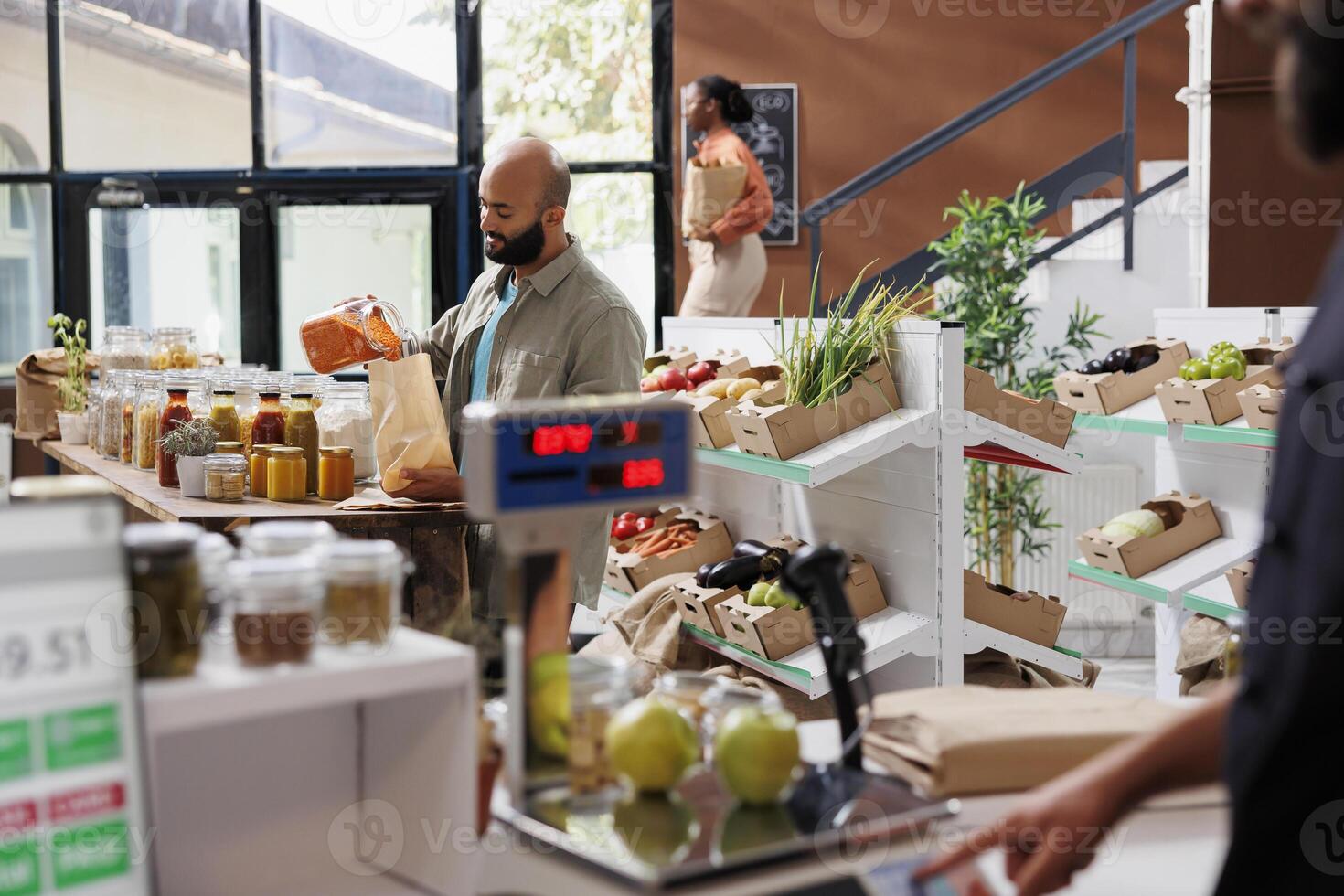 In a bio grocery store, male customer buys grains from local vendor and bulk products using biodegradable bags. Sustainable lifestyle, middle eastern man pouring natural pantry items from jars. photo