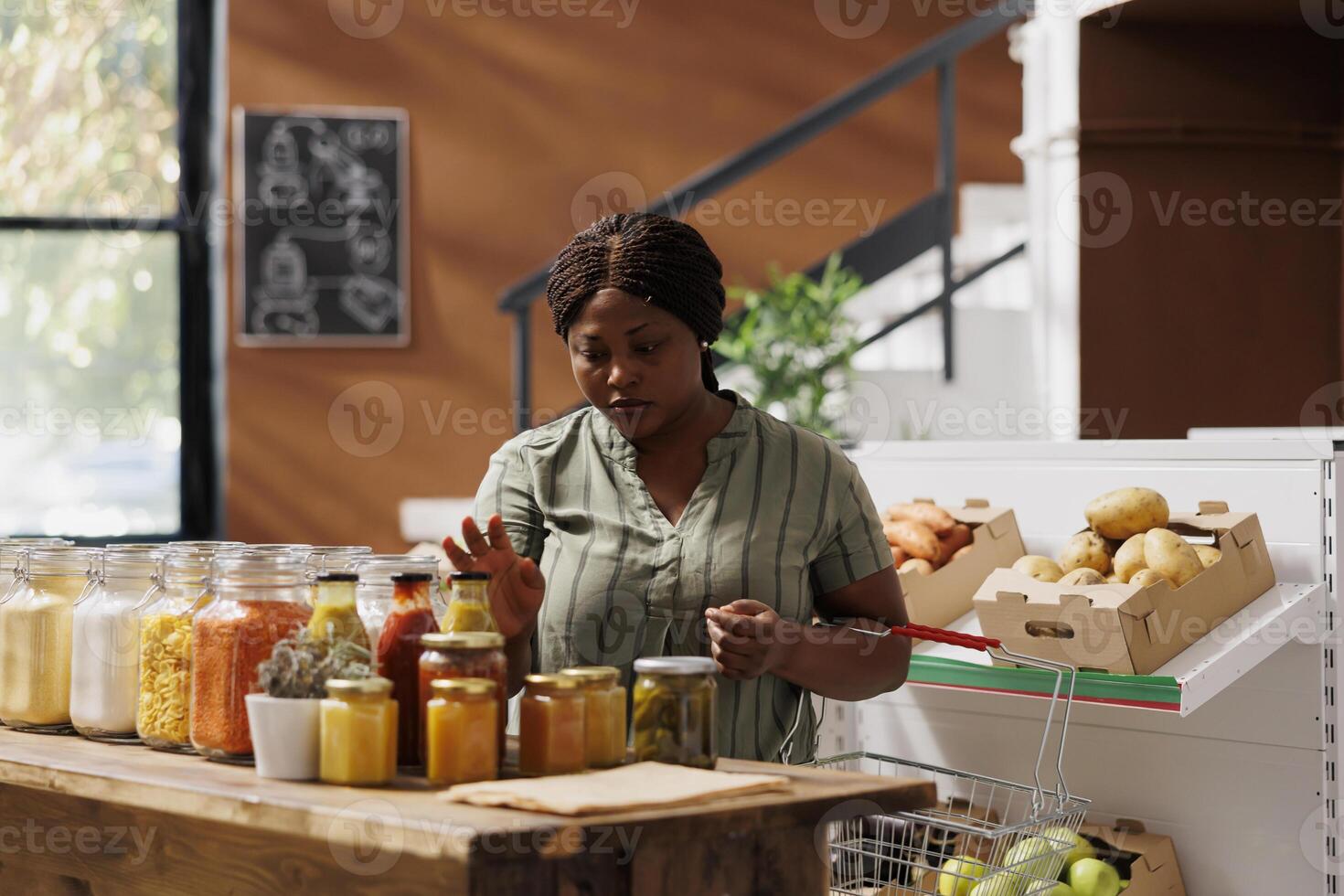 Woman searches for eco friendly products in a supermarket, browsing jars of freshly harvested food. She chooses paper bags, supporting a zero waste lifestyle and small businesses. photo