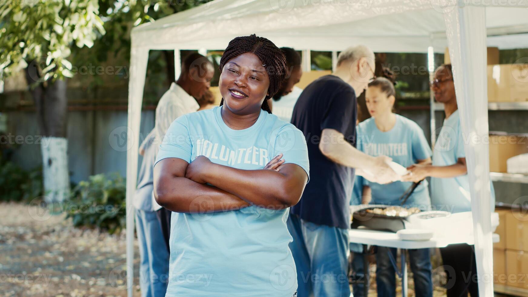 At food drive charitable event, african american female volunteer smiles and poses. Humanitarian aid program providing hunger relief and assistance to homeless and those living in poverty. photo