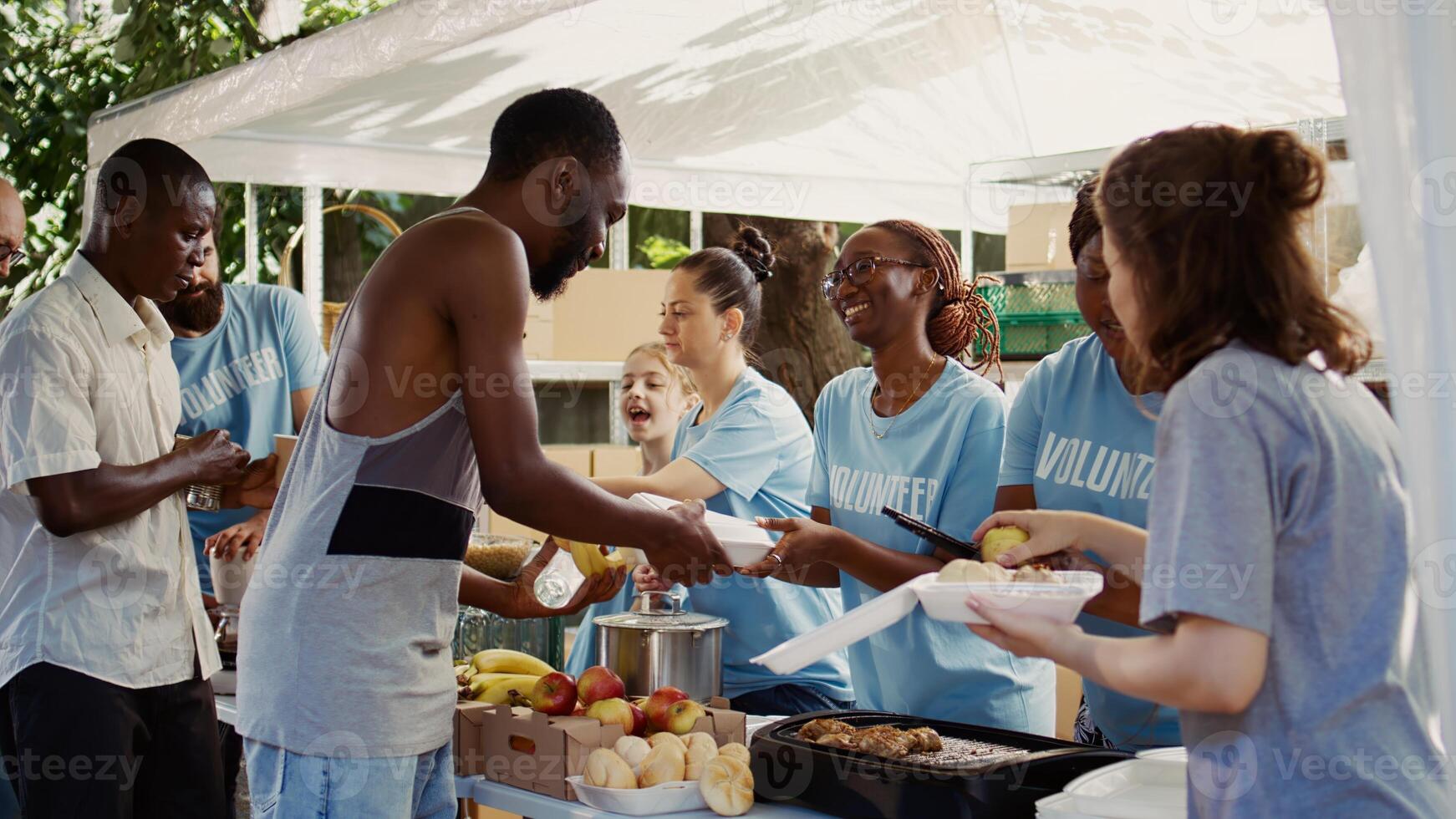 Multiethnic voluntary individuals distribute donated food, extending a helping hand to homeless and hungry people. Young volunteers share fresh, complimentary meals with those less fortunate. photo