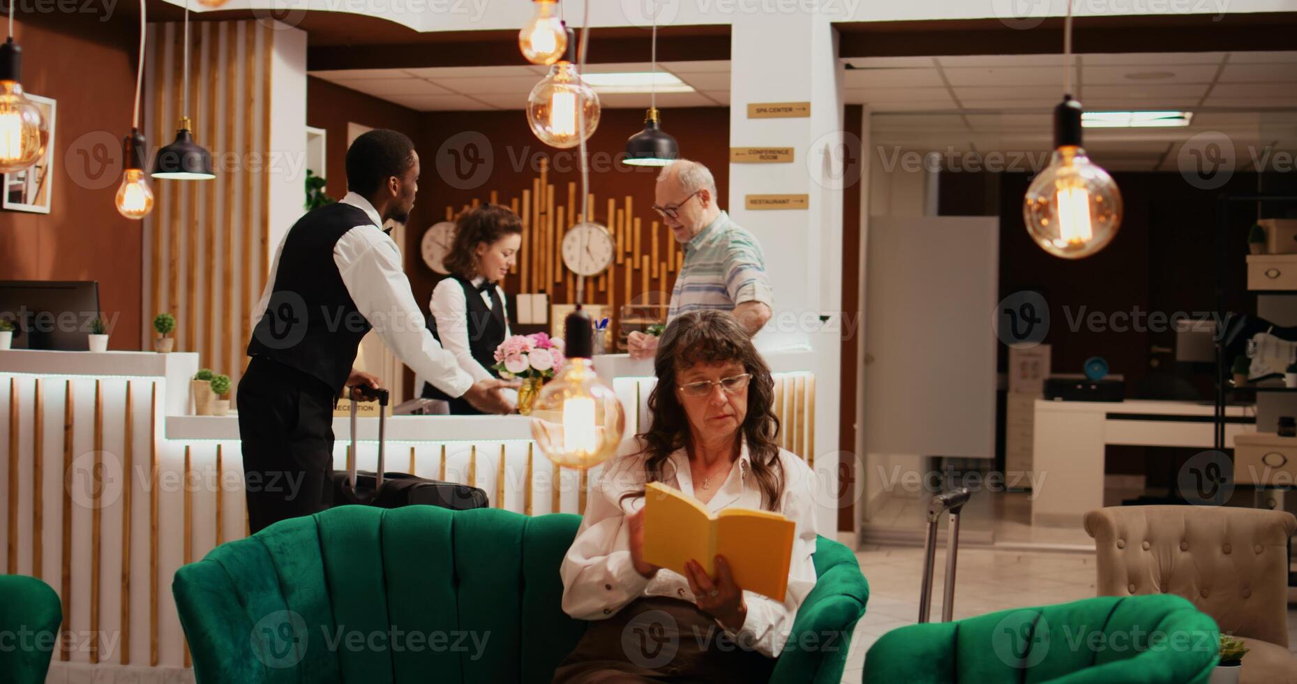 Receptionist gives access key card to hotel guest, finishing with check in process and heading to room with bellhop. Concierge employees assisting senior man to ensure relaxing trip. photo