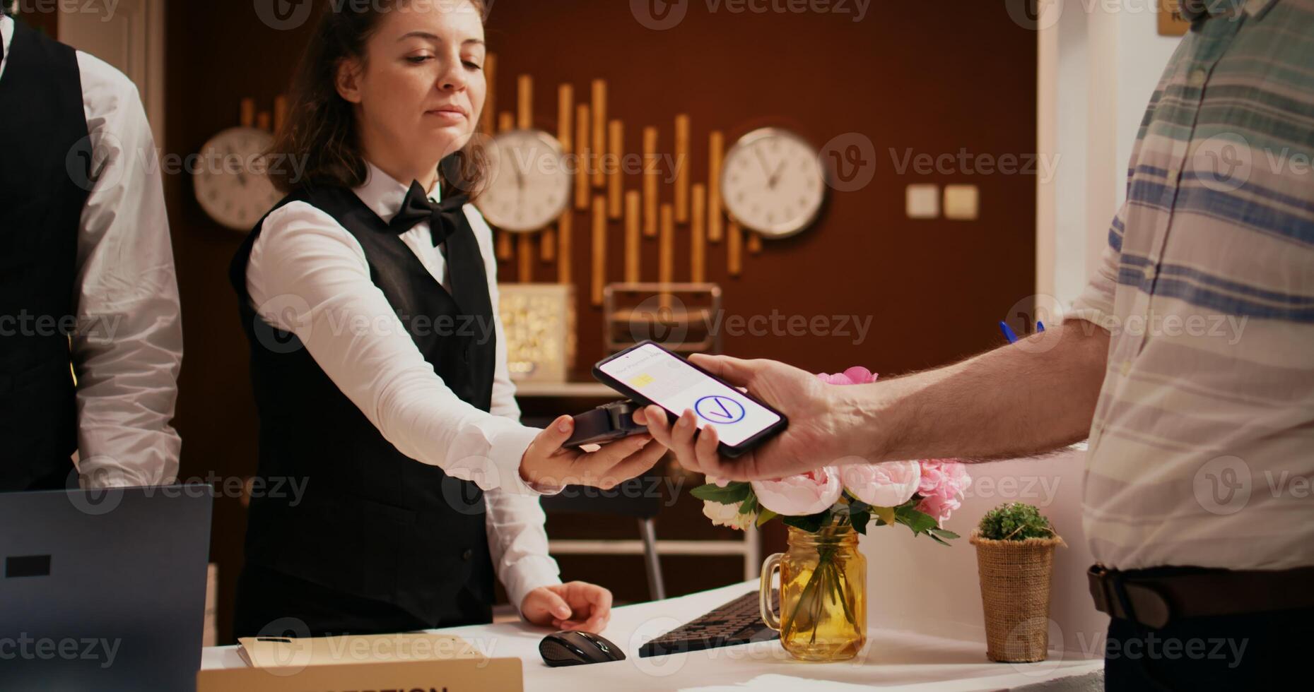 retirado invitado utilizando móvil pago con nfc tecnología a pos Terminal, pago para hotel habitación a recepción frente escritorio. antiguo hombre registrando a fiesta retiro, haciendo electrónico transacción. foto