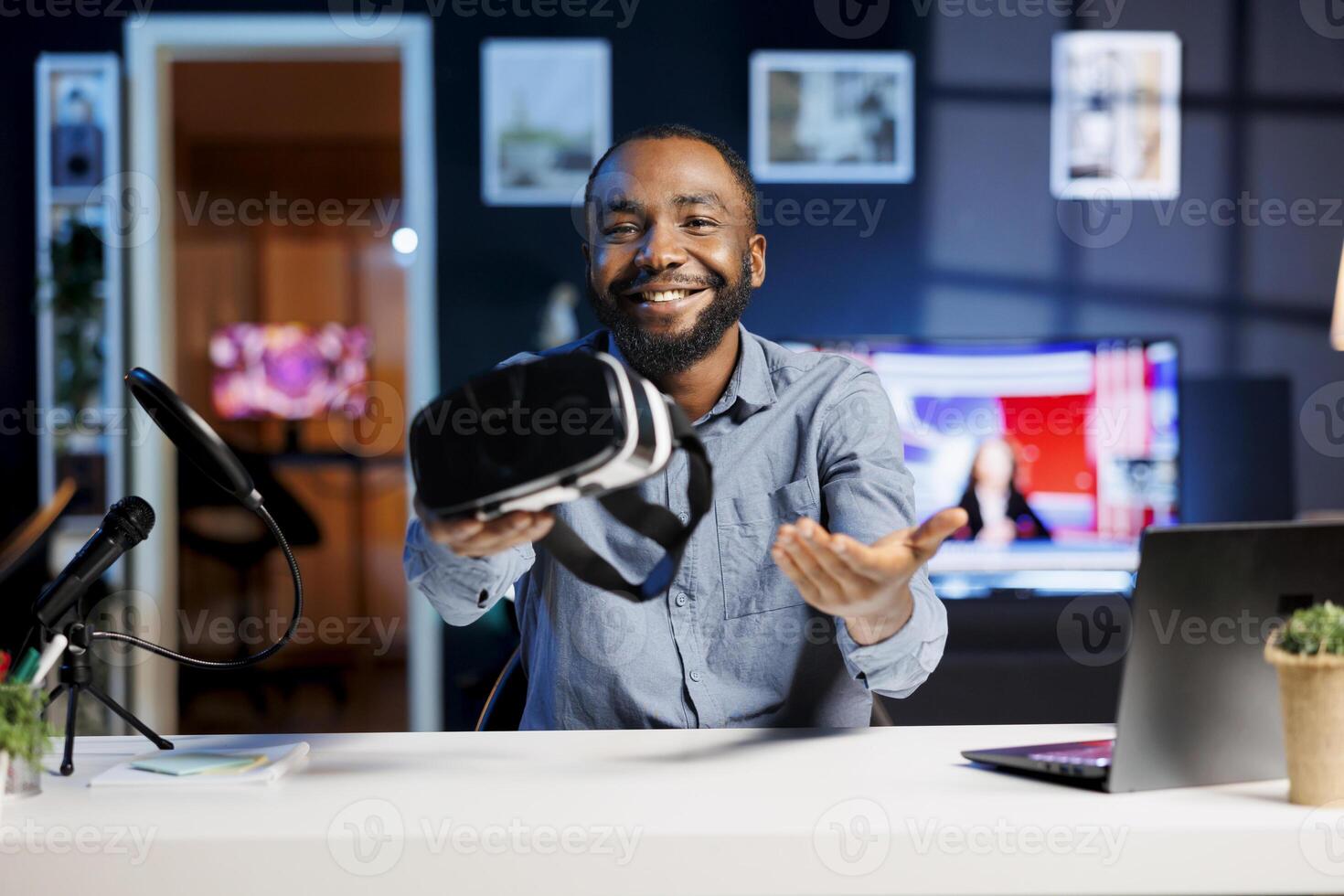 Internet show host presenting VR goggles to audience, filming video with professional camera. Content creator recommending virtual reality headset product to fans after testing it photo