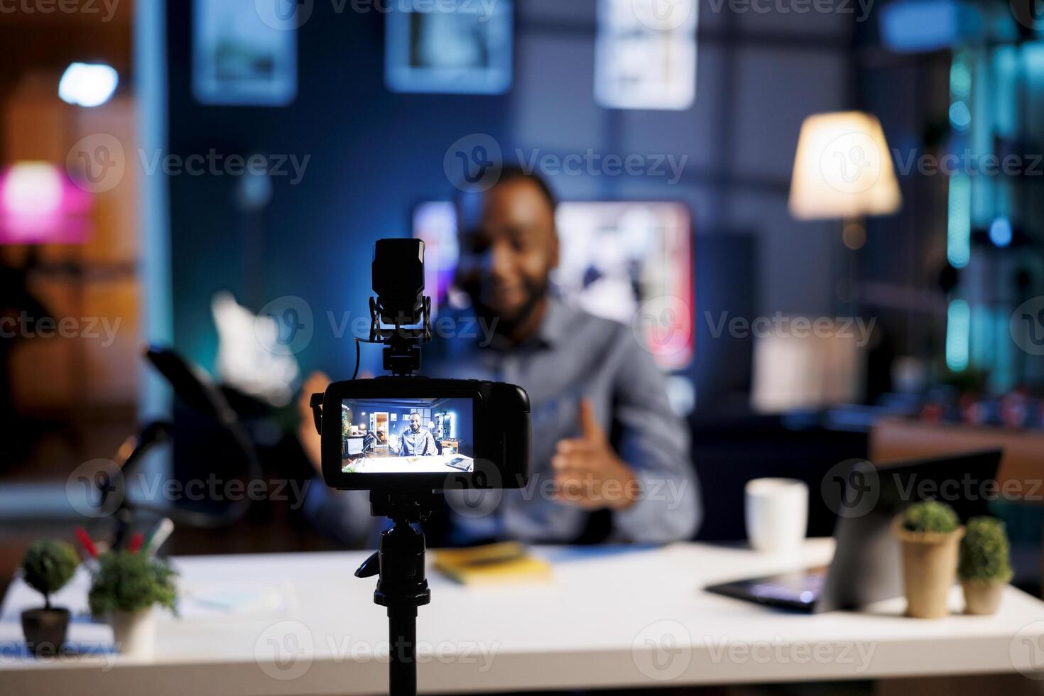 Professional camera used to record tech tutorial on how to repair damaged electronics. Technology guru in blurry background using video production gear to produce content for audience photo