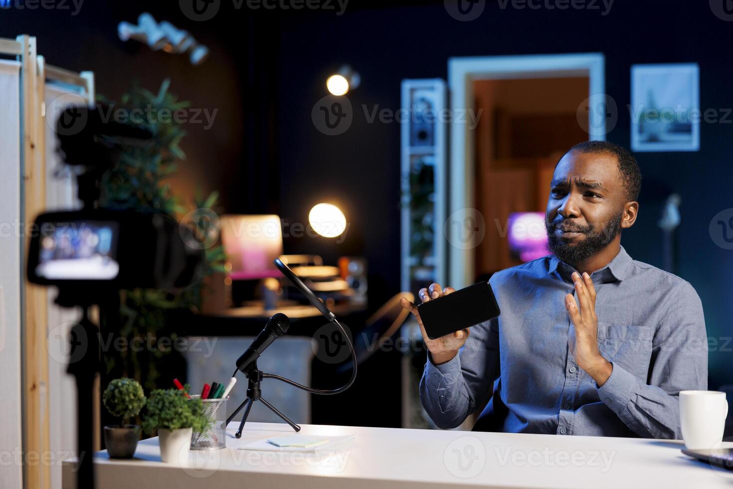 Content creator using professional recording tech to film smartphone review for online audience. Internet show host using technically advanced camera to capture mobile phone presentation photo
