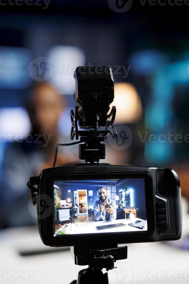 Focus on professional camera capturing footage of media star in blurry background filming tutorial on how to do mouse maintenance, teaching viewers about fixing Bluetooth wireless computer peripheral photo