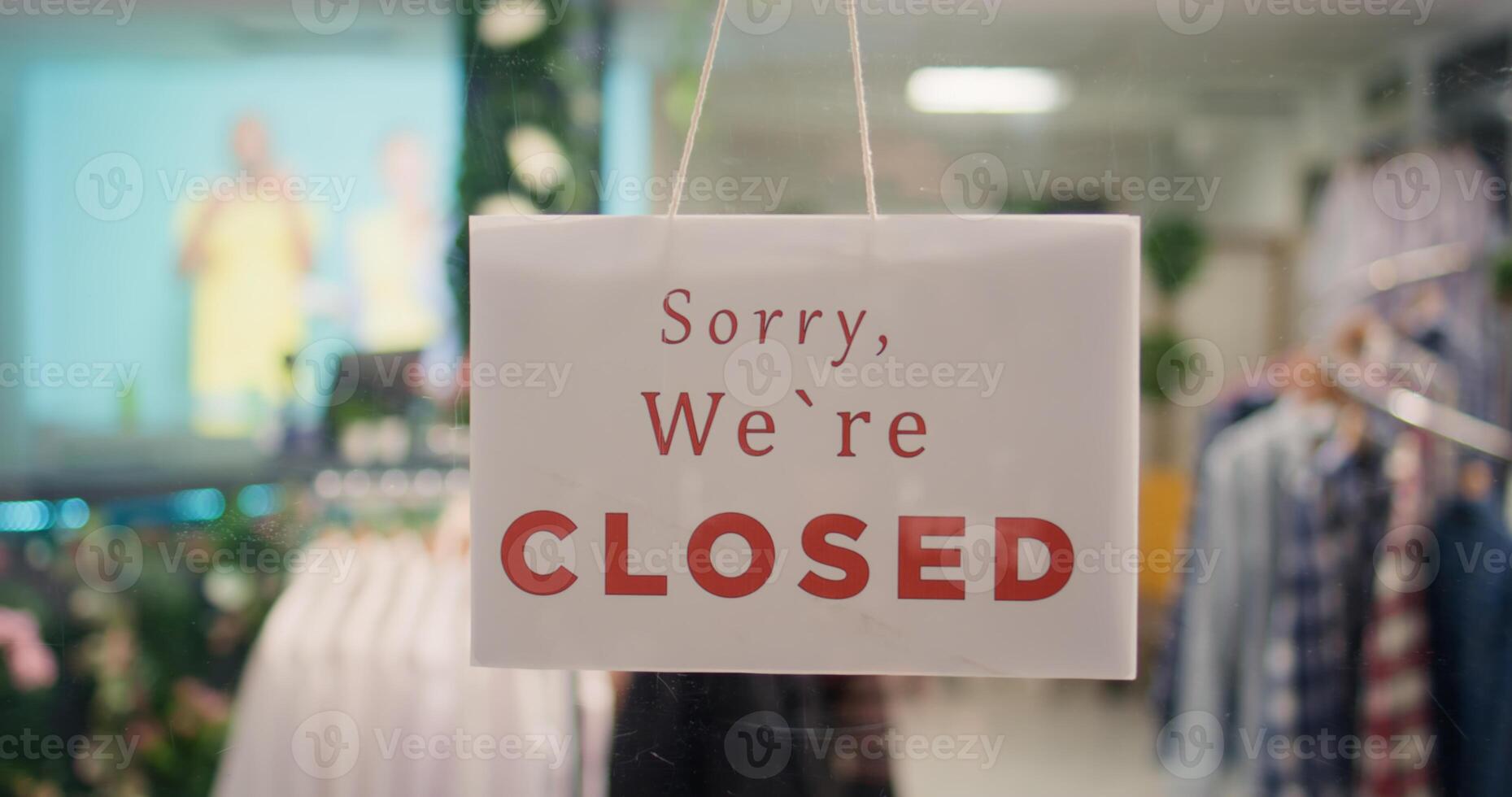 Extreme close up shot of close sign in expensive clothing store with elegant assortment of trendy clothes. Zoom in on sorry we are closed message on premium fashion boutique door with attire garments photo