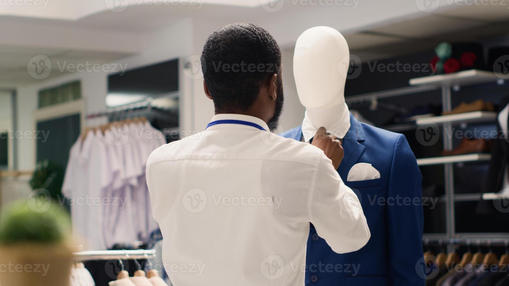 Employee tightening elegant blazer necktie on mannequin in luxurious clothing store. Worker arranging new collection stylish high class attire garments in premium fashion boutique photo