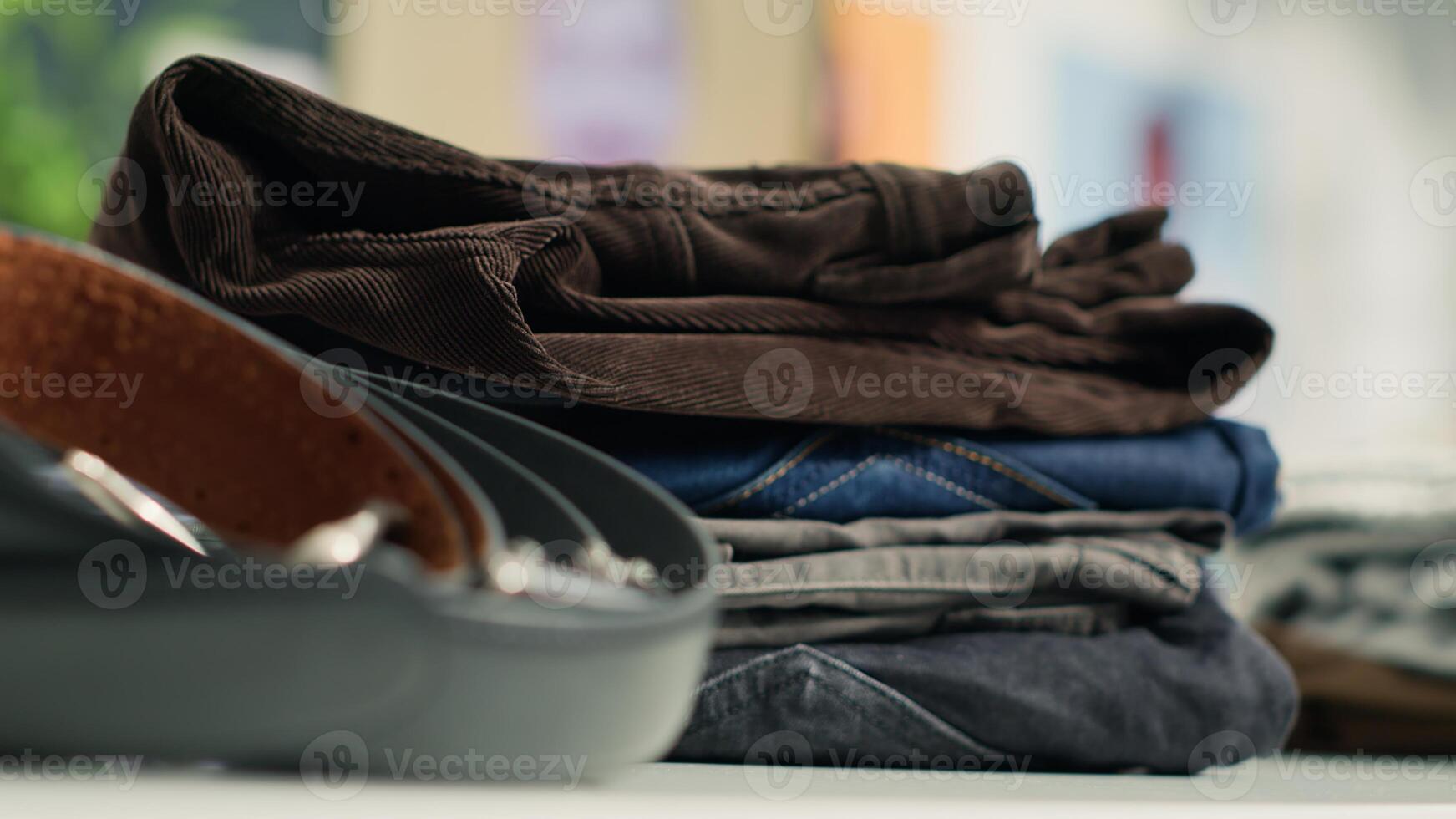 Close up shot of cheap and sustainable designer clothing in empty zero waste shopping outlet saving clothes from reaching landfill. Zoom in shot on trousers and belts in eco friendly second hand store photo