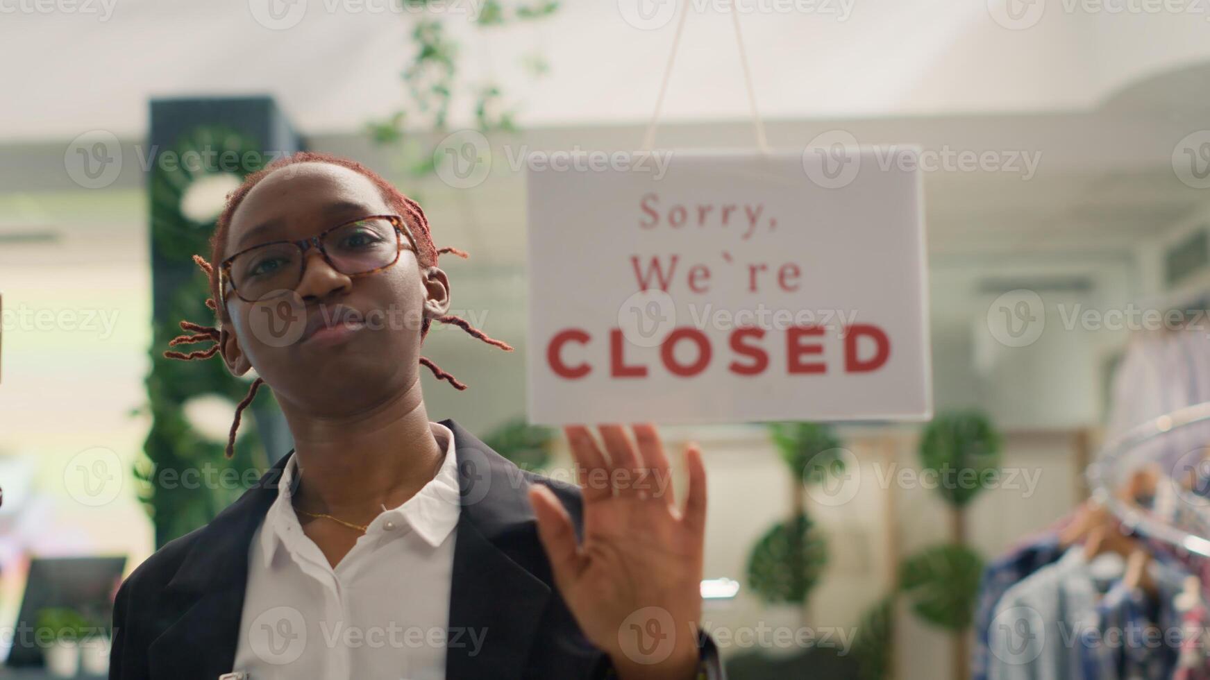 African american shop assistant closing fashion boutique business, ending her shift at night. Storekeeper turning opened sign on fast fashion clothing store into closed one after working hours photo