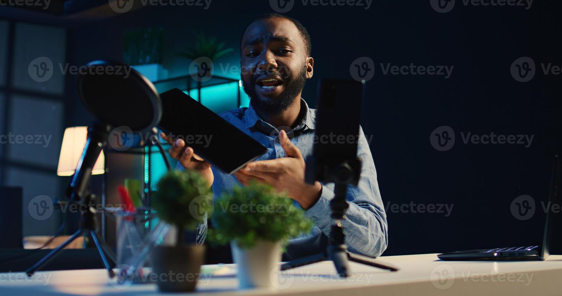 Content creator in studio films tablet video review for tech enthusiasts. African american viral online star hosts technology internet show, unboxing digital portable device photo