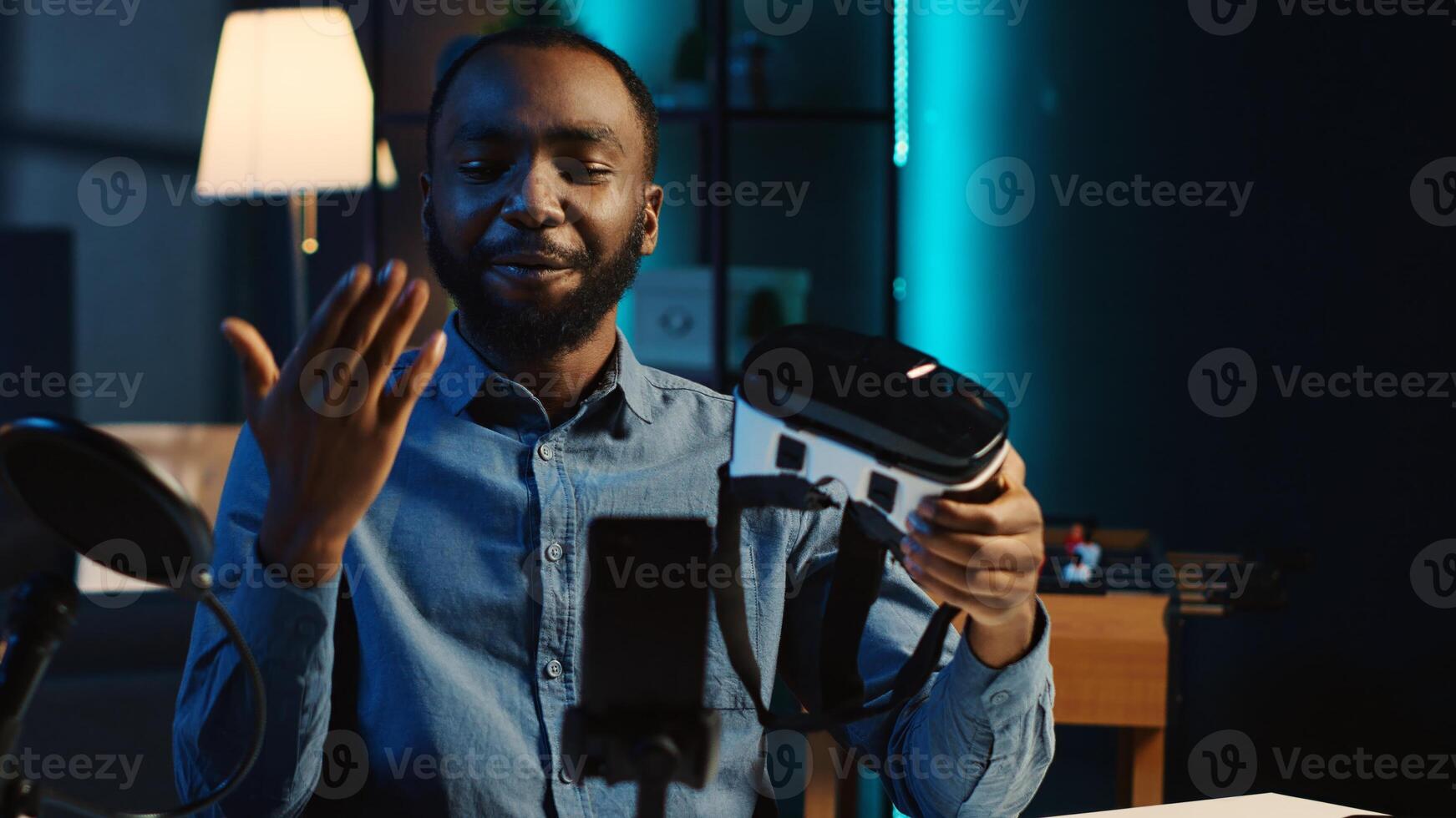 Tech content creator filming technology review of newly released gaming VR glasses for audience in home studio. BIPOC influencer showing virtual reality headset to subscribers photo