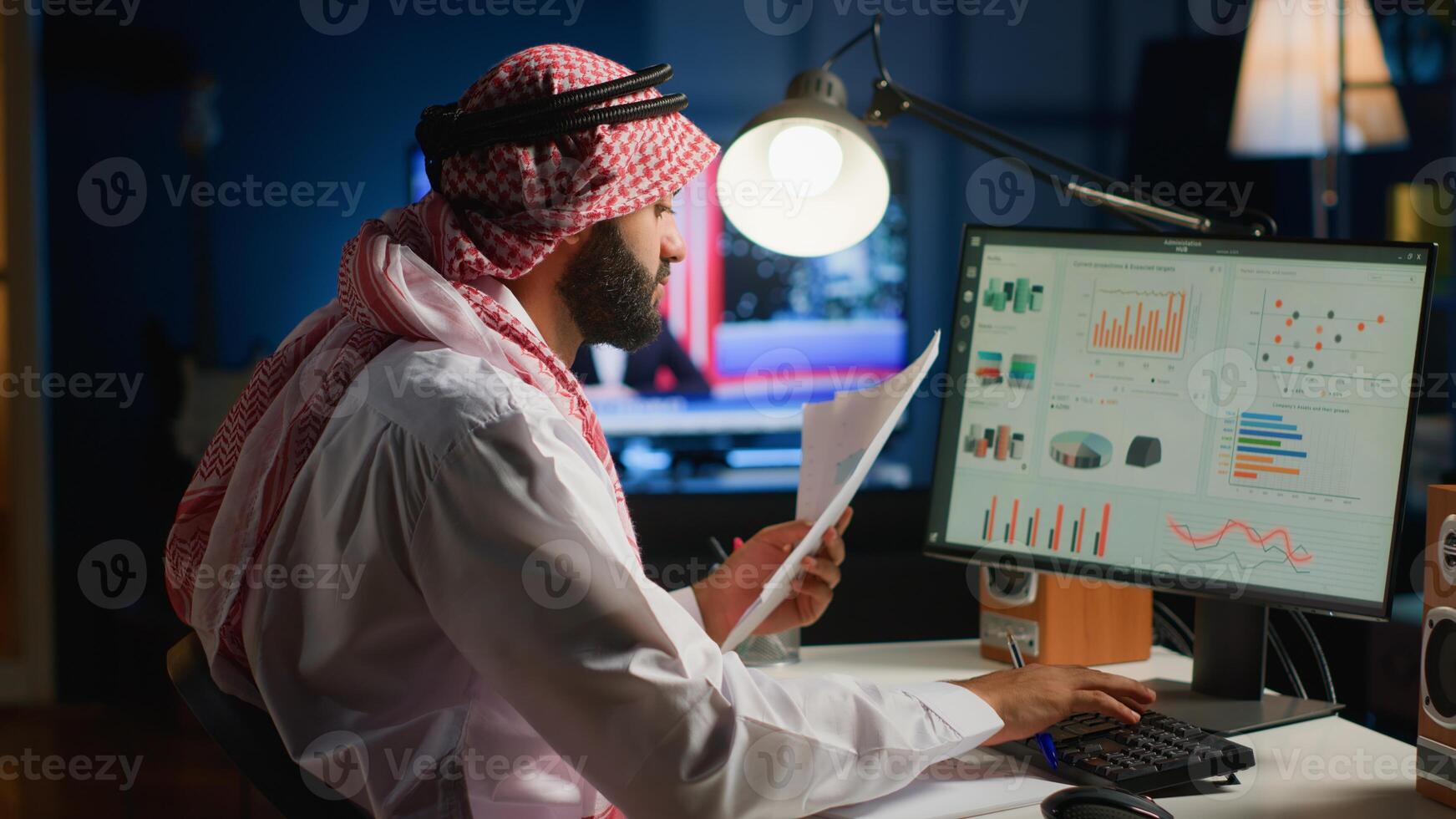 Arab teleworker checking analytics statistical data set while remotely working in stylish apartment. Business manager optimizing key performance indicators with tv as background noise photo