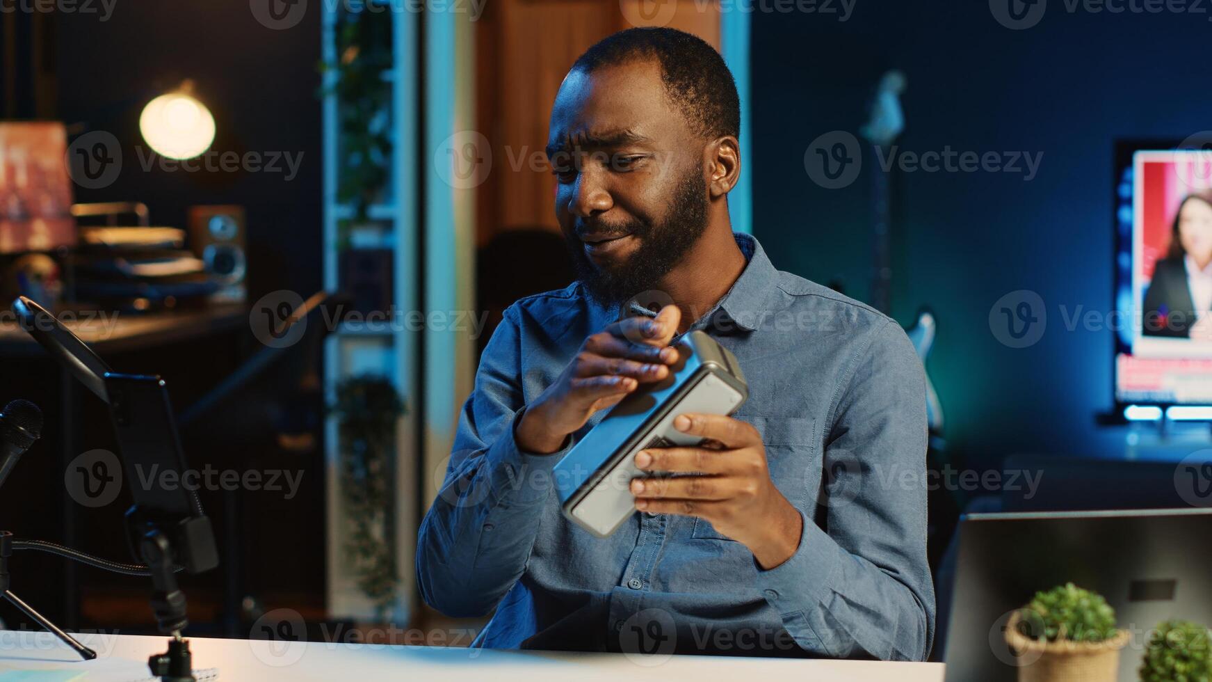 African american internet star doing technology review of Bluetooth portable speaker for online platforms channel. BIPOC influencer presenting music playing device to his viewership photo