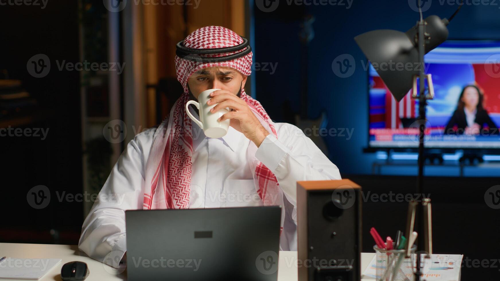Arab job candidate enjoying beverage while remotely being interviewed by human resources team. Muslim man drinks coffee while getting his credentials checked during online video conference meeting photo