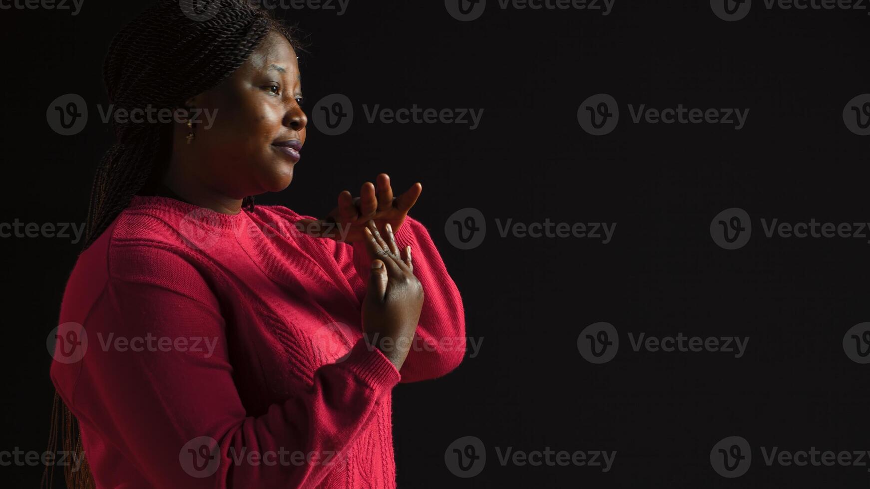 Side-view portrait of female model performing timeout, pause motion on camera. African american woman in black background displaying a t shape stop symbol with her arms, indicating no. photo
