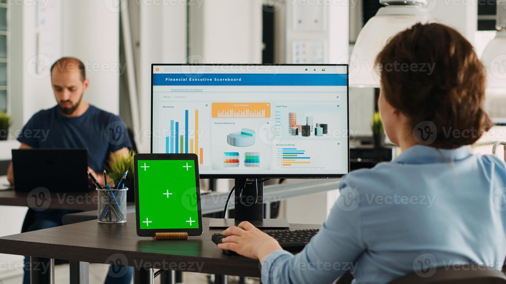 Business person using pc at workstation, having greenscreen display template on tablet in front of her. Manager planning startup operations and checking isolated mockup layout on device. photo
