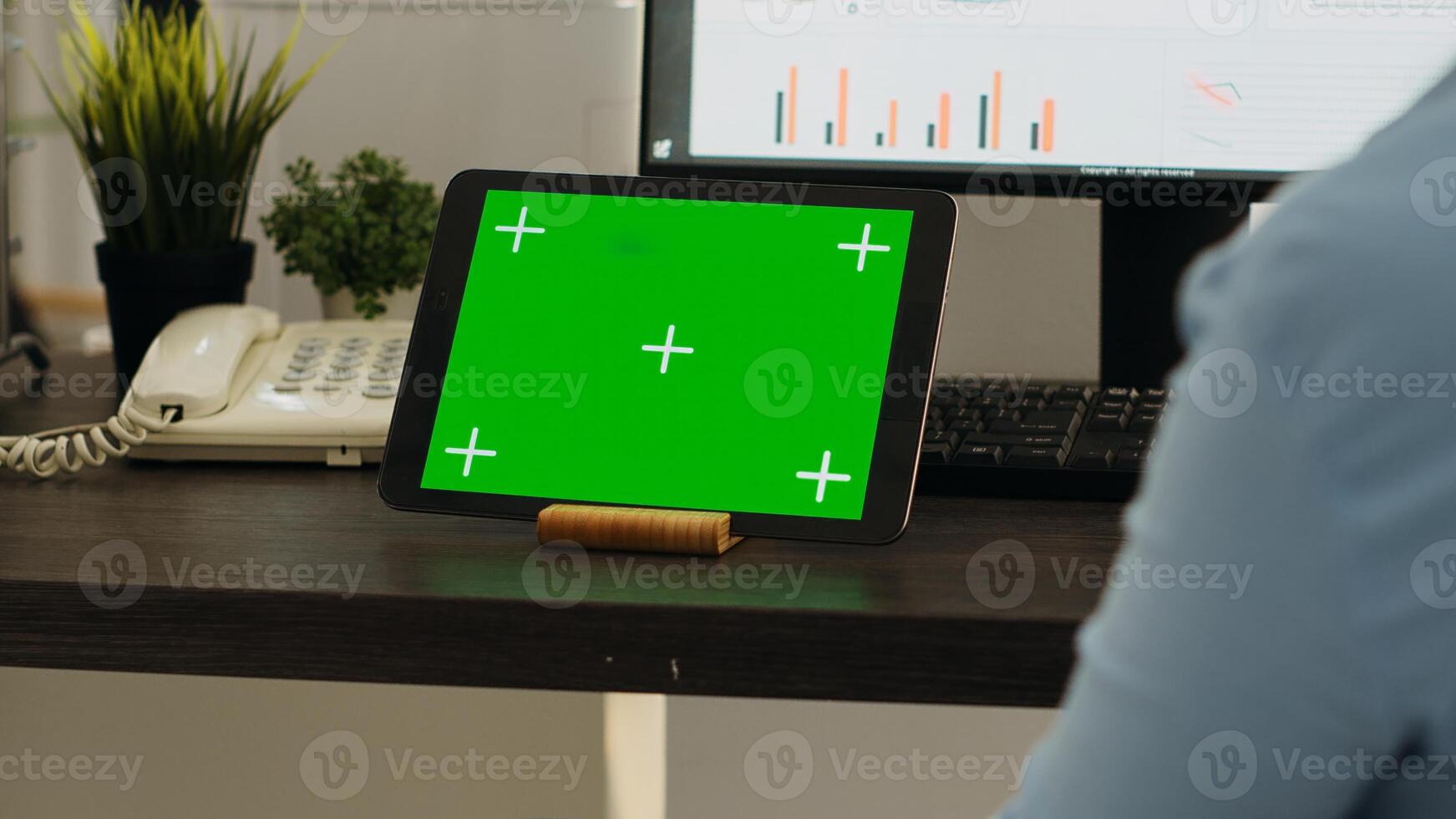 Woman works at office desk and uses modern gadget to present greenscreen display, problem solving in coworking space. Young person employee looking at blank mockup chromakey template. photo