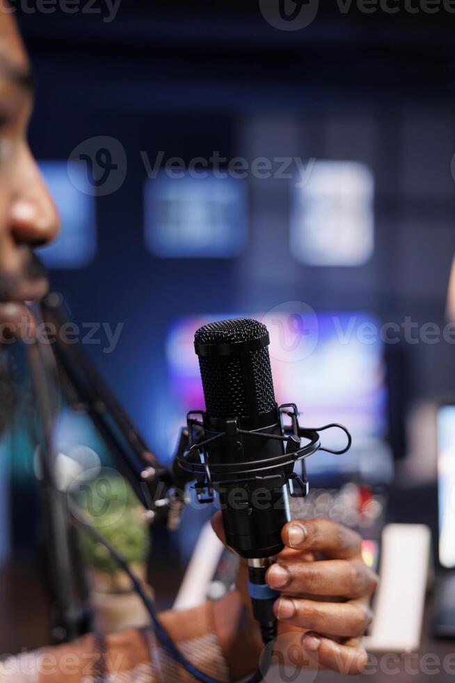 Male presenter recording live talk show using professional audio equipment at home. African american man speaking into microphone doing an online production, creating a podcast episode. photo