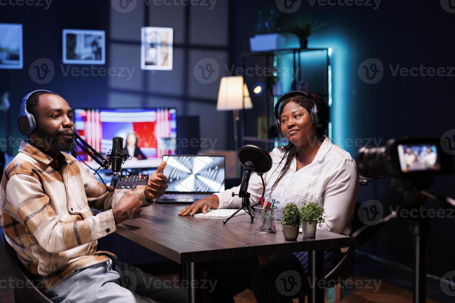 African American influencers in a cozy home studio, wearing headphones, engage their audience in an interesting online discussion. Black content providers recorded a vlog for social media platforms. photo