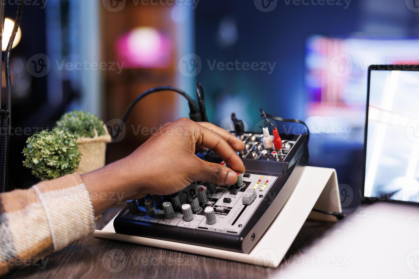 Detailed view of black person adjusting sound mixer to achieve high-quality recording during the podcast episode. African american individual turning an audio equipment knob while hosting a talk show. photo