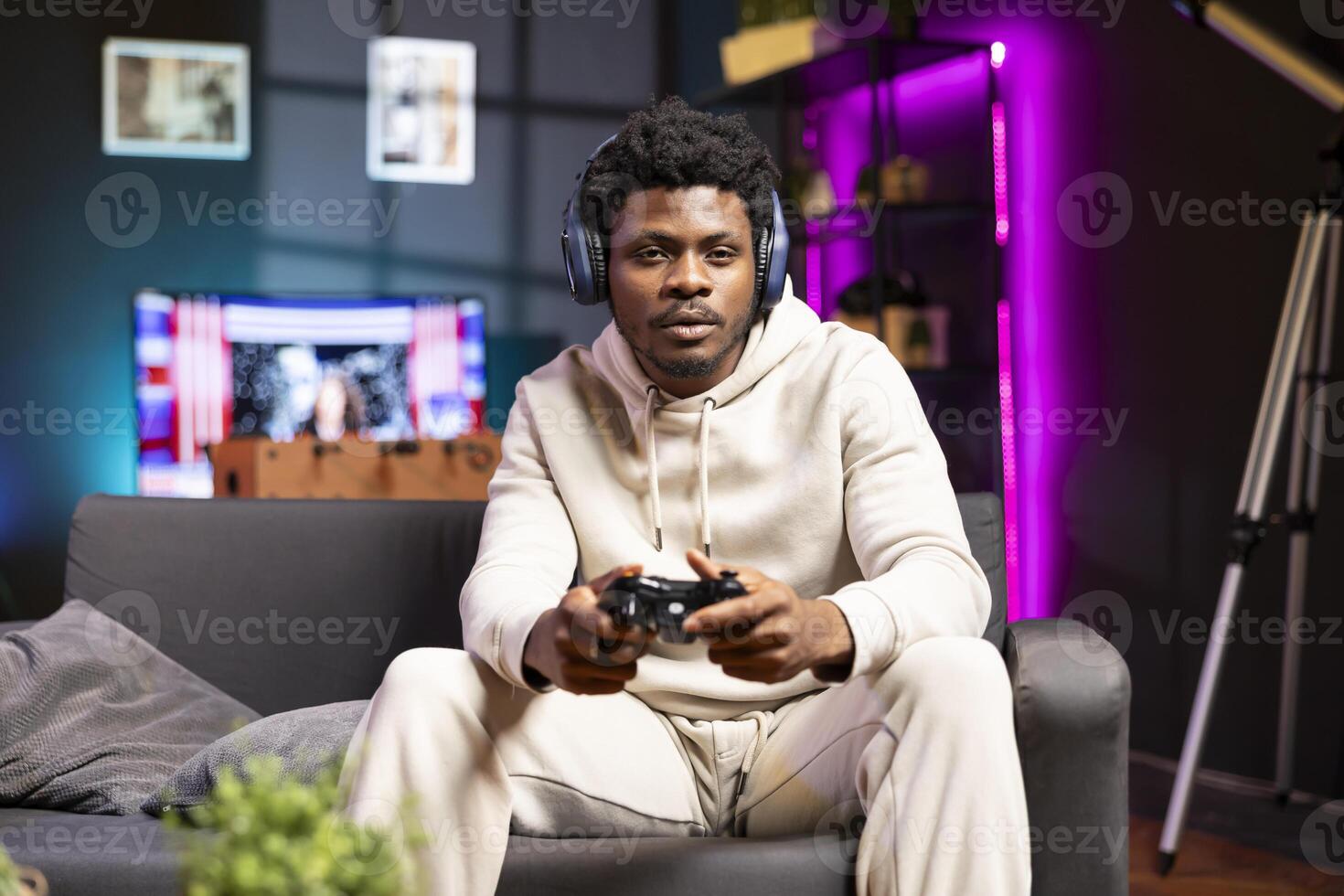 Man sitting on couch at home, relaxing by playing videogames on gaming console. BIPOC gamer unwinding in living room by competing in online multiplayer esports tournament photo