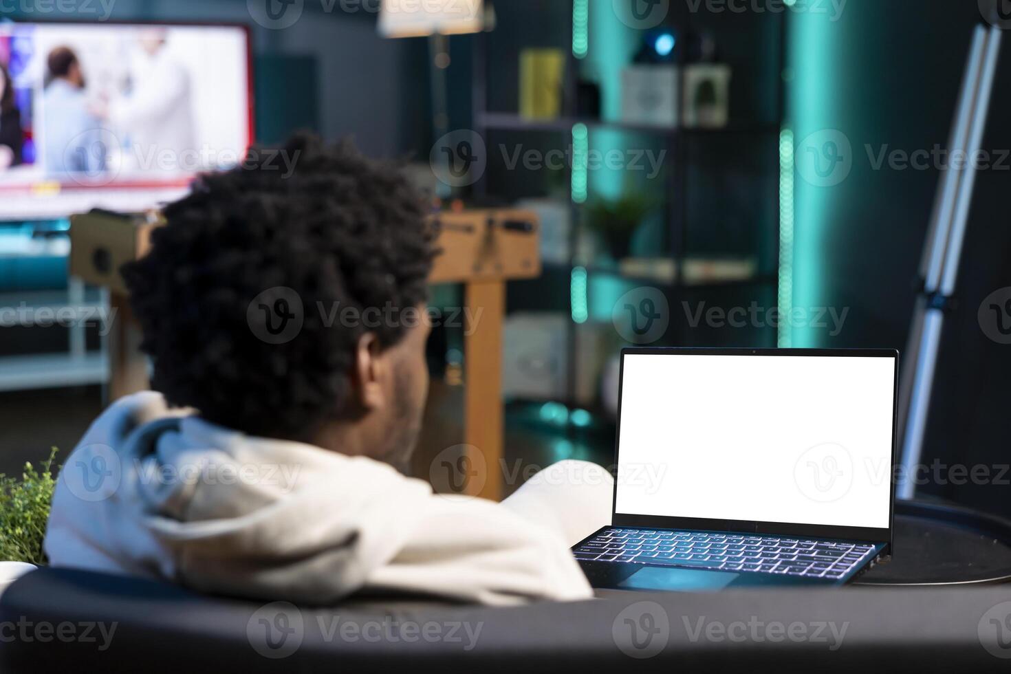Remote employee inputting data on mockup laptop display while working from home, looking at screen. Teleworker lying on couch, remotely performing tasks on isolated screen notebook in living room photo