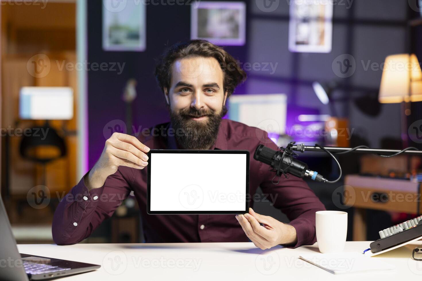 Portrait of smiling man in studio filming tech tutorial on how to do maintenance on mockup broken tablet. Online show host teaching subscribers how to open and fix isolated screen digital device photo