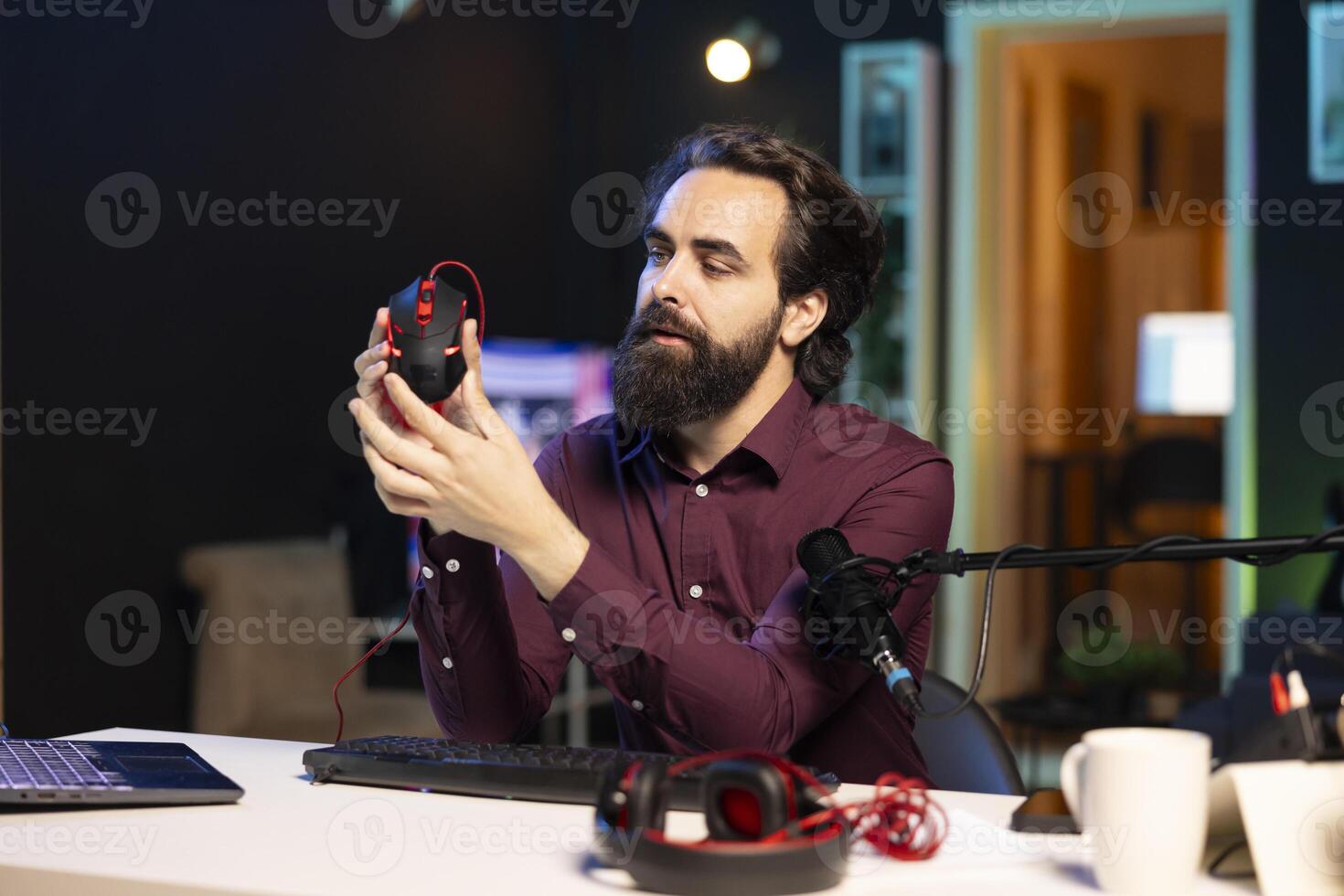 Tech guru filming technology review of wireless gaming mouse for audience using professional microphone. Content creator inspecting computer peripheral device, recording with specialized mic photo