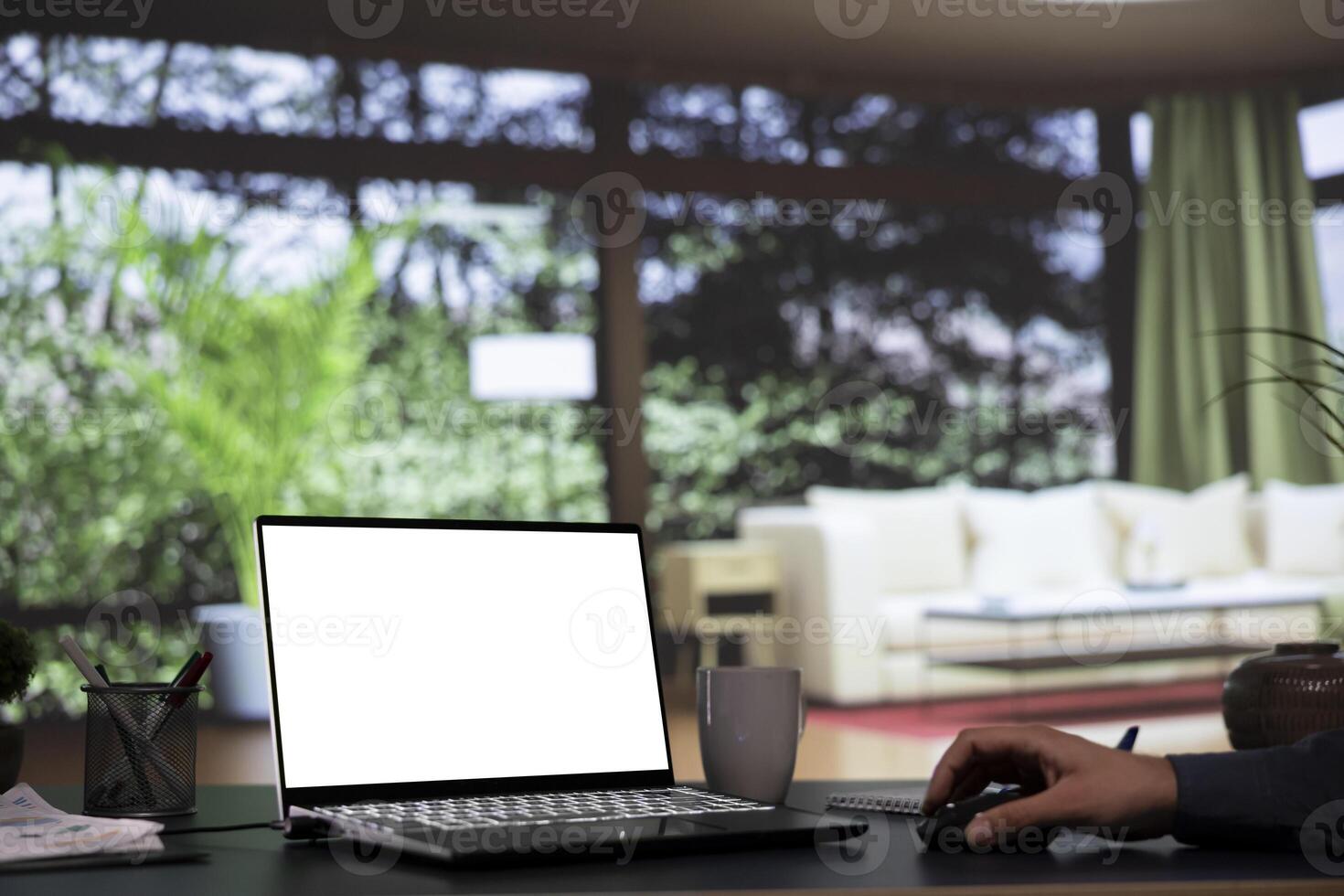 Wealthy tycoon relaxes at his opulent mountain cabin, working with blank display template on laptop. International company director connects on pc with white screen, wealthy lifestyle. photo