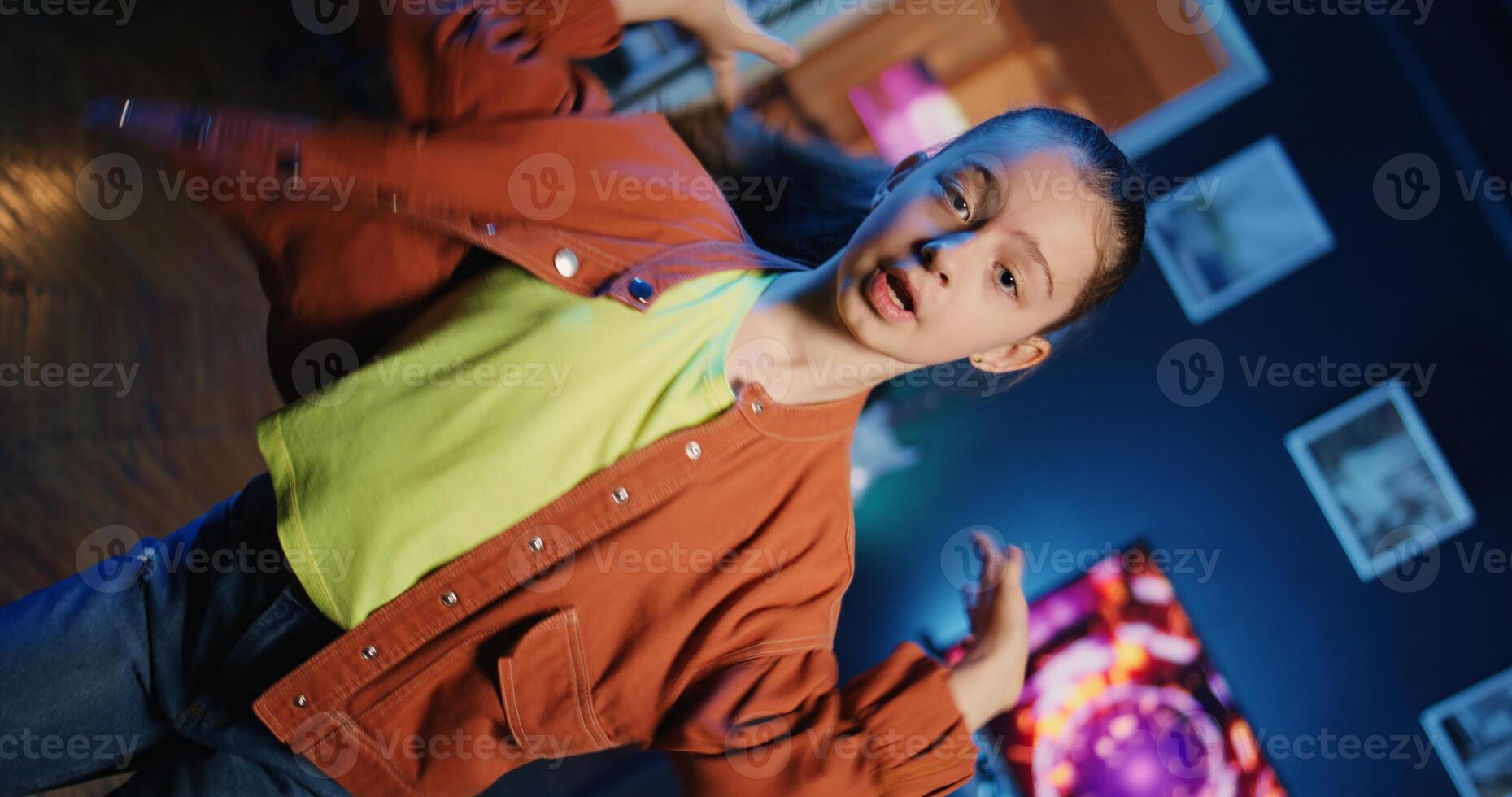 Charming girl getting tons of engagement on her dancing clips posts recorded at home. Child filming viral videos in living room, impressing children viewers with dance moves, close up shot photo