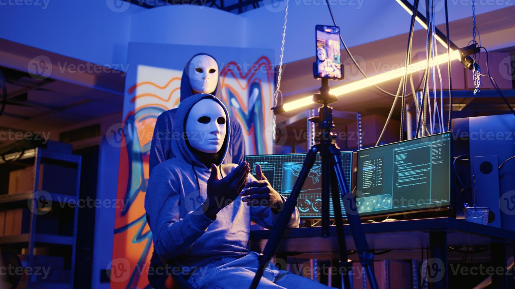 Anonymous evil developers filming ransom video in hidden underground base, threatening to release stolen data publicly if payout demands are not met, using cellphone to record blackmail footage photo