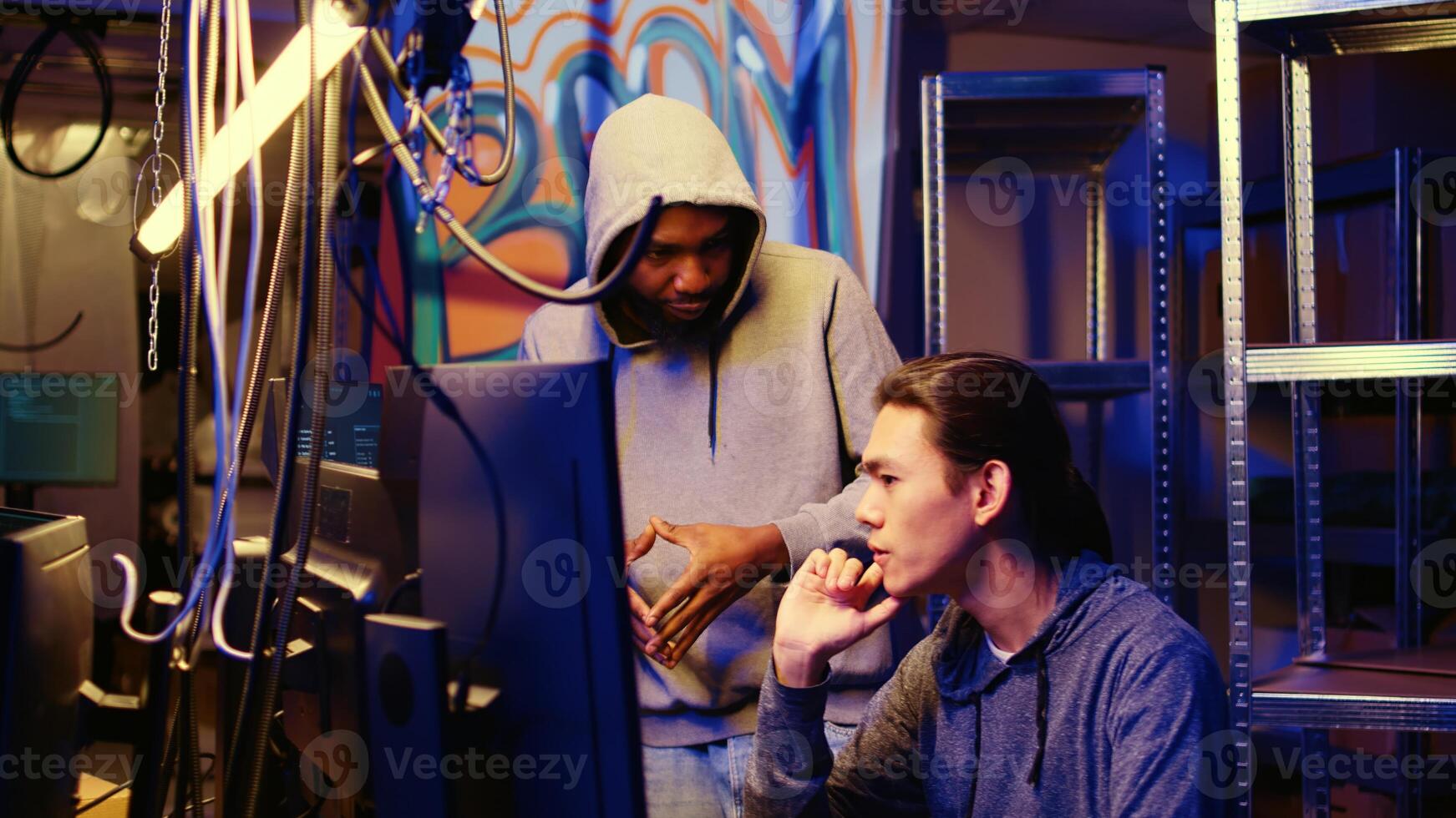 Hackers in underground hideout discussing ways to best hide their online activity through VPN and other methods after stealing data from victims, trying to avoid being detected by cybercrime police photo