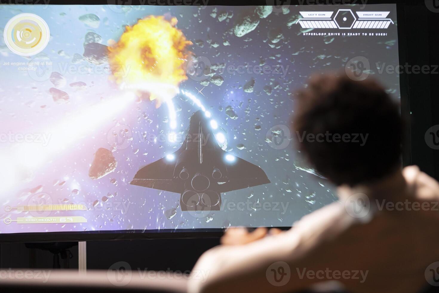 Gamer playing classic arcade action videogame on ultrawide smart TV, flying through space debris. Man enjoying leisure time at home using high tech gaming console and controller to solve missions photo