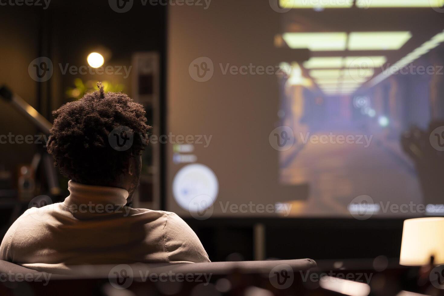 BIPOC man playing singleplayer videogames on widescreen TV, relaxing after long day at work. Gamer enjoying science fiction first person shooter game on gaming console, shooting enemies photo