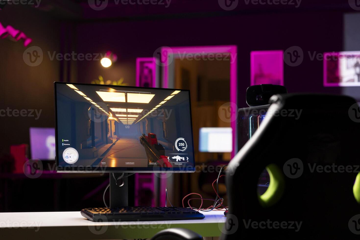 Professional gaming empty room studio with neon lights and RGB lit powerful computer, first person shooter game left open on screen. FPS videogame on pc display in apartment late at night photo