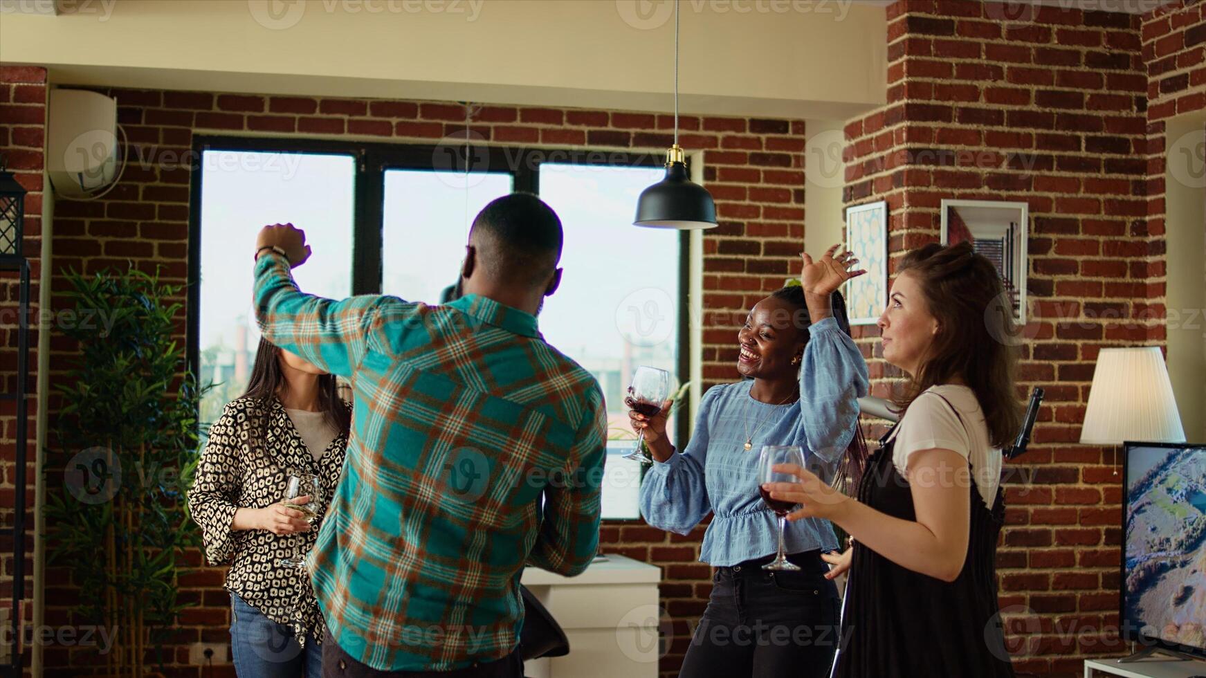 Multicultural mix of guests at apartment party sharing laughter and dance moves, creating vibrant atmosphere in living room. Happy friends dancing on electronic beats during weekend hangout photo