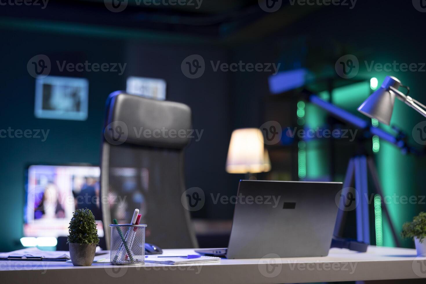 Modern decor surrounds a laptop, desk, and comfortable chair in a casual home office setup. The room has a startup vibe thanks to the lack of formality, which is ideal for remote or freelance workers. photo