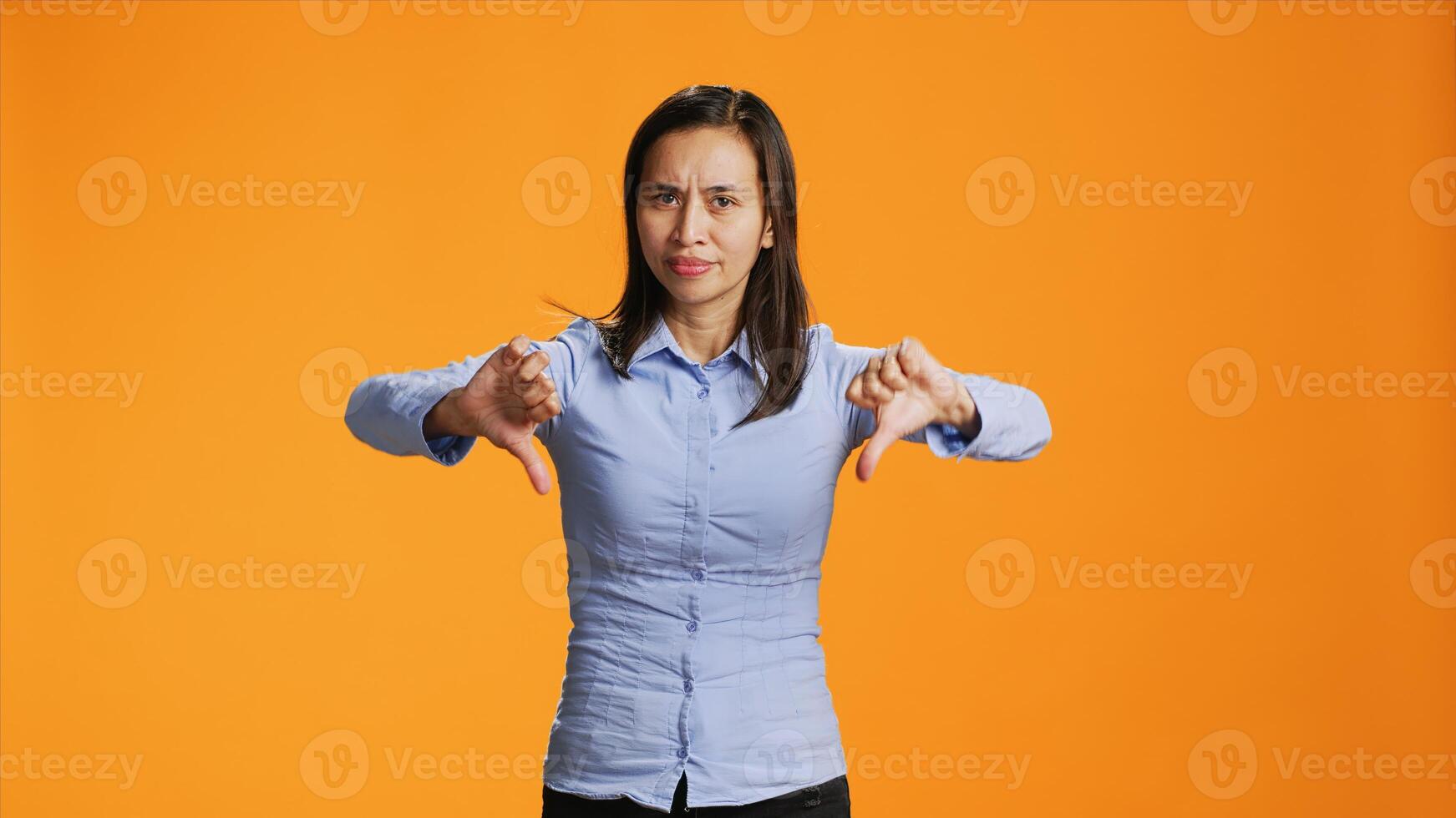 Filipino girl does thumbs down sign on camera, presenting negativity and disagreement with bad gesture symbol. Negative woman expressing her refusal, being upset and unhappy. photo