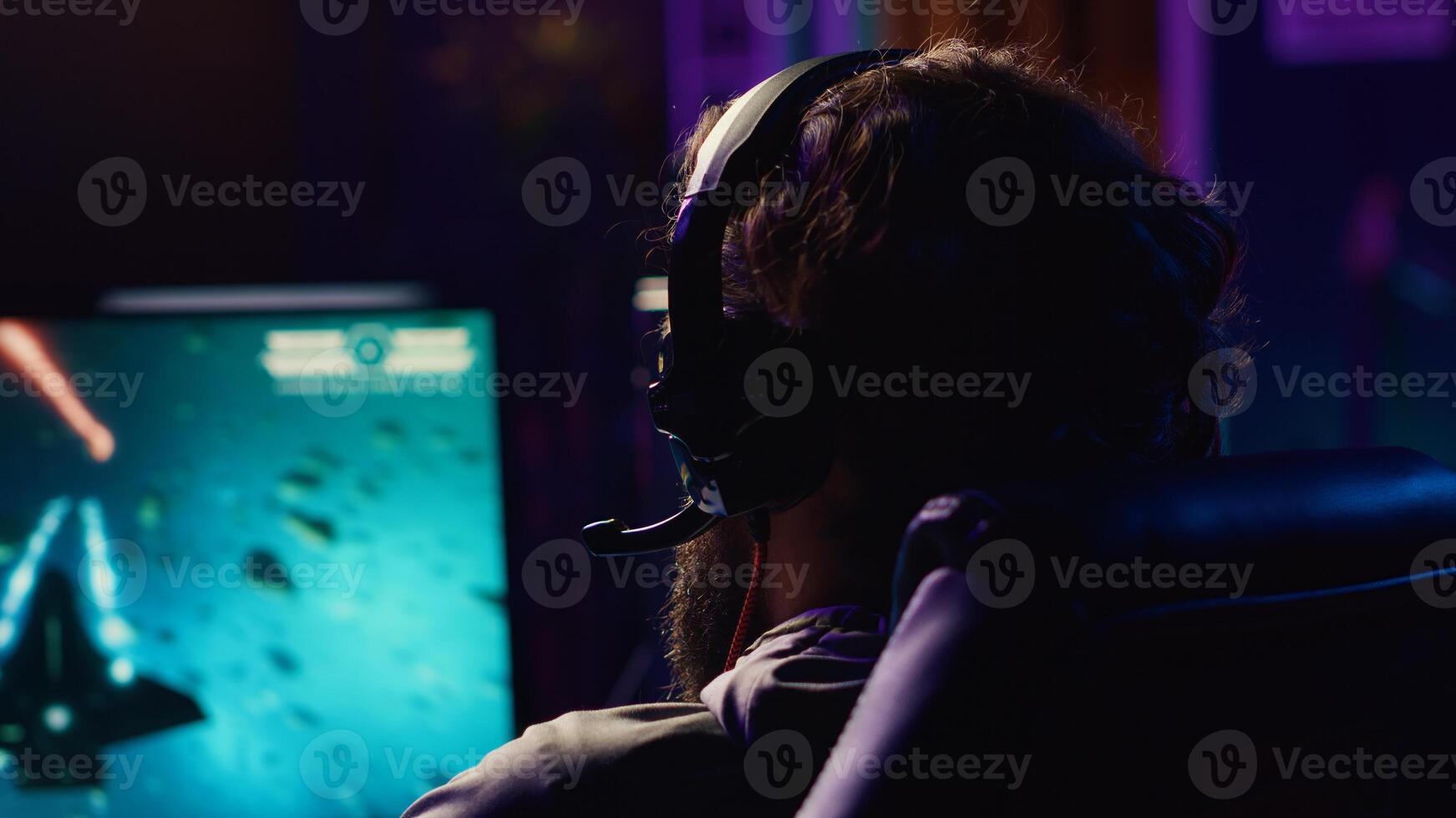 Man plays online multiplayer spaceship videogame with friends, using headphones for immersive experience. Player using gaming setup to flying spacecraft in flight game, enjoying leisure time photo