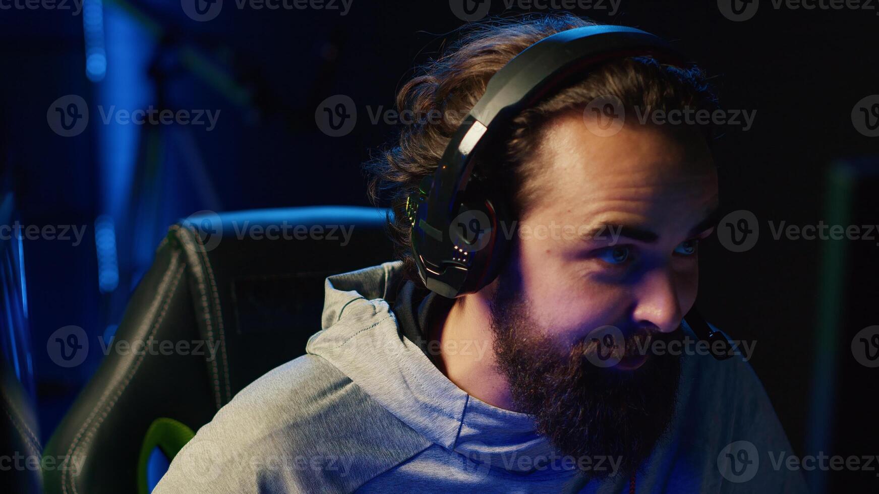 Esports player playing videogames in front of subscribers during livestream, providing knowledgeable commentary during gameplay. Zoom in on professional gamer streaming game in dark studio photo