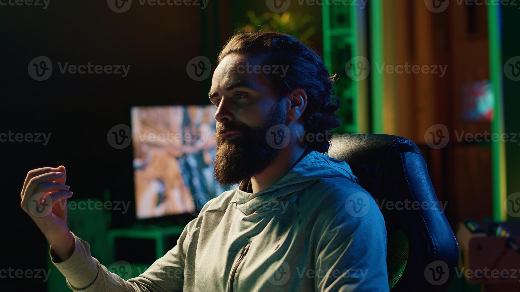 Man playing videogames live while chatting with online audience from RGB lit living room. Professional gamer streaming multiplayer game while talking with internet subscribers photo