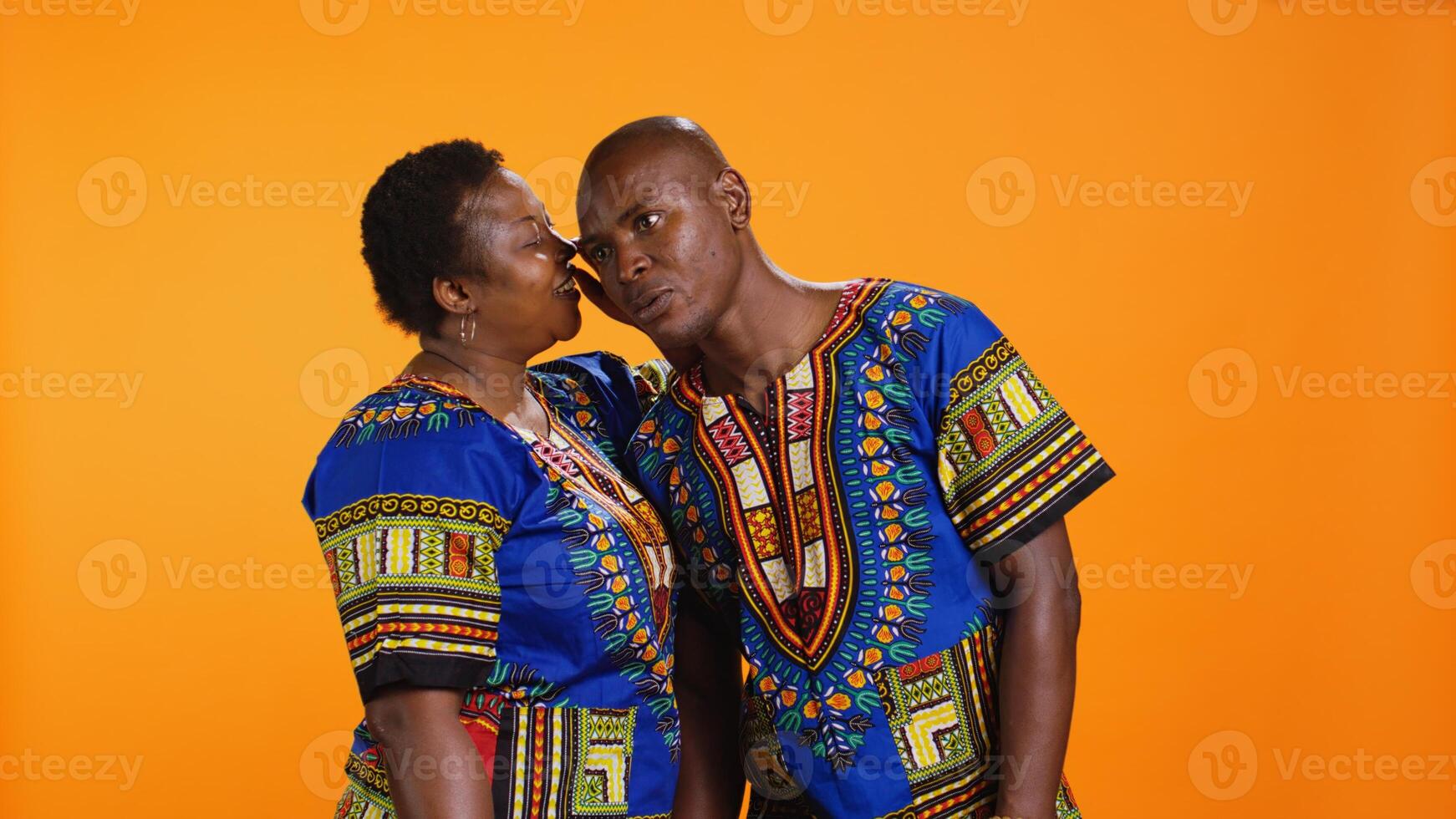 African american woman sharing a secret information, whispering something in her partner ear and gossiping in studio. Shocked man listening to confidential private details about someone, secrecy. photo