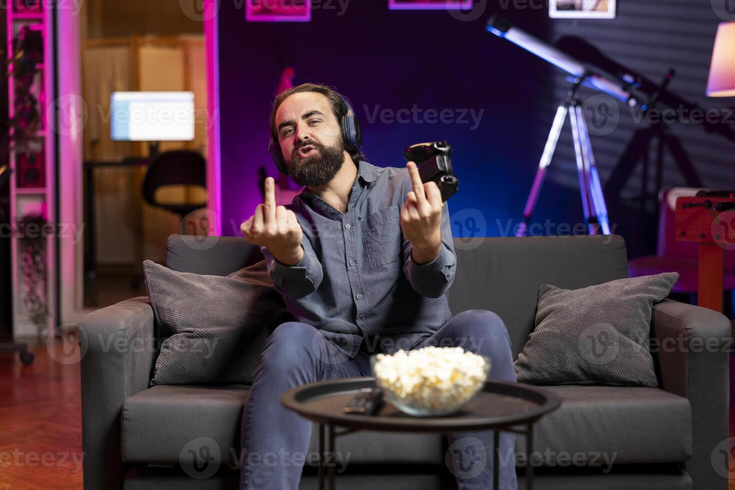 Happy gamer releasing pent up emotions after finally defeating enemies, showing middle finger sign. Man congratulating himself after winning videogame, feeling relieved, doing vulgar hand movements photo